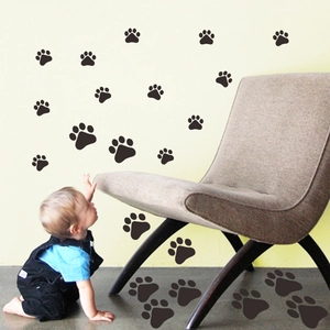 Enfant jouant près de stickers muraux et de sol empreintes de pattes de chien noires