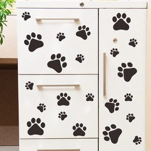 Stickers muraux empreintes de pattes de chien noires sur la surface d'un meuble blanc