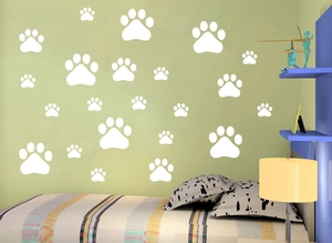 Détail de stickers muraux empreintes de pattes blanches sur un mur de chambre vert clair