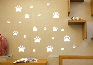 Détail de stickers muraux d'empreintes de pattes blanches de différentes tailles sur un mur