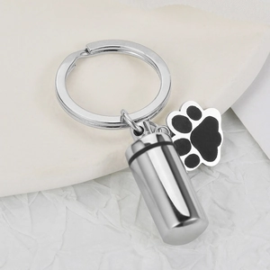 Macro shot of polished stainless steel pet cremation urn pendant and paw print keychain