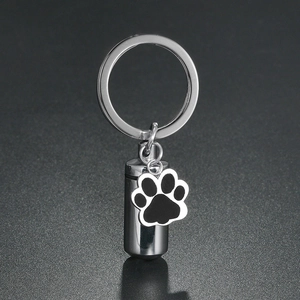Stainless steel pet memorial urn keychain with cylindrical capsule and paw print charm