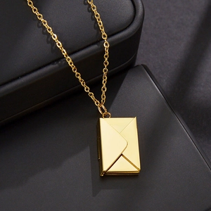 Detalle de un collar con colgante de sobre dorado sobre una caja de joyas negra mate