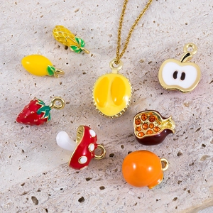 Garden style enamel fruit and vegetable pendants with a golden necklace on stone background