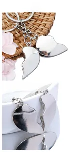 Detail of silver heart-shaped couple keychain set displayed on a rustic woven mat