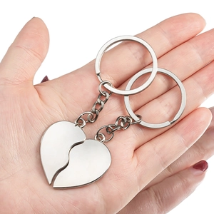 Pair of interlocking silver heart-shaped alloy keychains held by hand for couple or friends