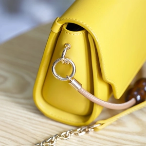 Elegant yellow leather shoulder bag with gold ring hardware and metal chain strap detail