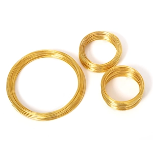 Three rolls of gold memory steel wire for DIY jewelry making on a white background