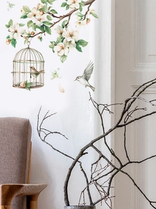 Scenic wall sticker detail with white flowers, birdcage, and birds on a clean white wall