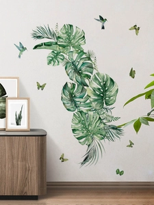 Detail of tropical monstera leaves and hummingbirds wall decals on a minimalist white wall