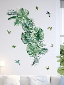 Detail view of tropical monstera leaves and hummingbird wall decals in a living room