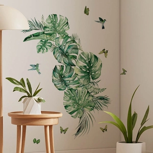 Tropical monstera leaves wall decal with hummingbirds and butterflies in a modern living room