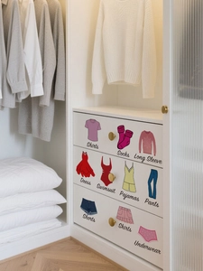 Detailed view of colorful cartoon clothing labels on minimalist white closet drawers