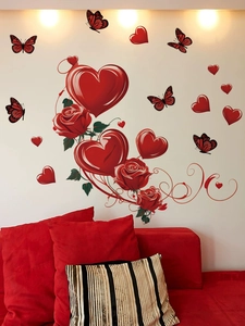 Detail of red rose and heart wall stickers on a white wall above a matching red sofa