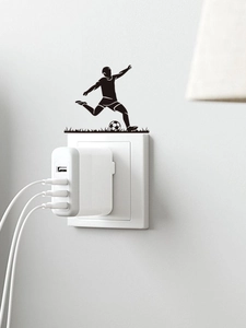 Close-up of a black soccer player silhouette sticker applied above a white wall outlet