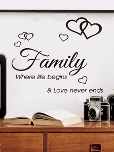 Close-up of Family quote wall decal with hearts on a white wall above a vintage camera
