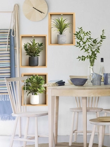 Detail of 3D wall-mounted wooden display frames with spotlights and artificial greenery