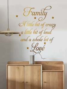Détail du sticker mural doré citation famille sur mur blanc au-dessus du meuble