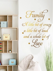 Détail d'un sticker mural doré avec citation familiale et étoiles sur mur blanc
