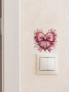 Detailed view of pink bow and heart sticker with floral motifs on a white light switch