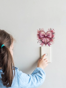 Detail of 3D pink heart and bow wall sticker applied above a light switch in a room