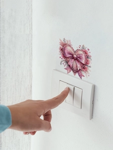 Detail of floral heart wall sticker with pink bow above a white light switch panel