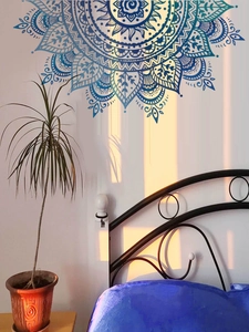 Detail of blue mandala wall decal above a black metal bed frame with sunset lighting