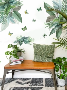 Close-up of tropical palm leaves and butterfly wall decals in a modern living room