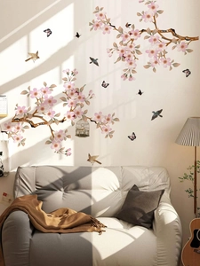 Peach blossom branches and birds wall decals shown above a gray sofa in a living room