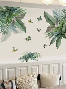 Close-up of tropical green leaves and butterfly wall stickers in a cozy home setting
