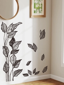 Detail of black minimalist leaf wall stickers applied on a white wall in a modern living room
