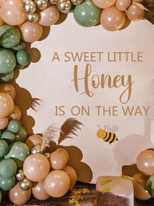 Baby shower backdrop with bee theme and gold script lettering on party wall decor