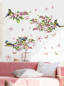 Detail of blue birds and pink cherry blossom wall stickers above a pink velvet sofa