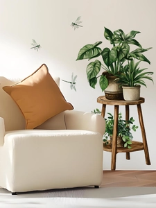 Detail von grünen Monstera Wandstickers und Vintage Holzschemel Dekoren für die Wand