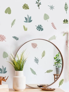Detail of tropical plant wall decals in Morandi colors around a round wooden mirror