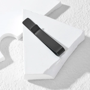 Macro view of minimalist matte black stainless steel tie clip on a white stone base