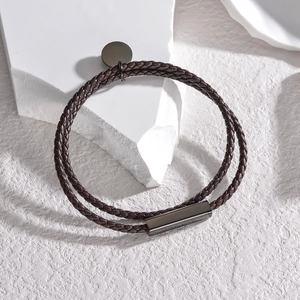 Detailed macro view of double-layer braided brown leather bracelet with gunmetal clasp