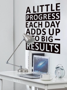 Close-up of black inspirational quote wall sticker above a minimalist desk setup