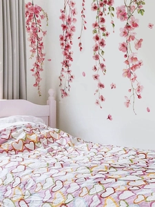 Detail of pink watercolor cherry blossom wall stickers in a cozy bedroom setting