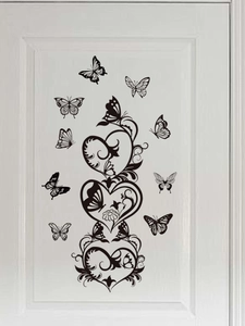 Close-up of black PVC butterfly and heart wall stickers on a white interior door