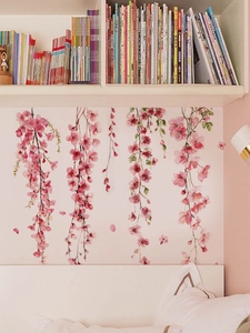 Detail of pink watercolor floral wall stickers hanging above a bedroom headboard