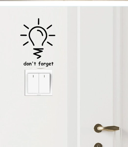 Close-up of black 'don't forget' light bulb wall sticker above a white light switch