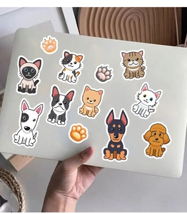 Detailed stickers of cute cats and dogs applied to a white laptop surface for decoration