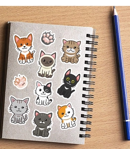 Close-up of nine assorted cartoon cat stickers and paw prints on a notebook cover