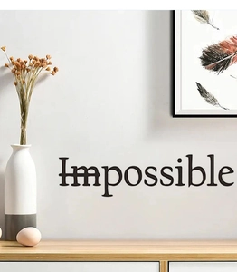 Close-up of 'Impossible' wall decal with 'Im' crossed out on white wall background