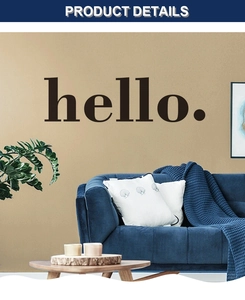 Detail of serif font HELLO wall decal on beige wall above a modern blue sofa