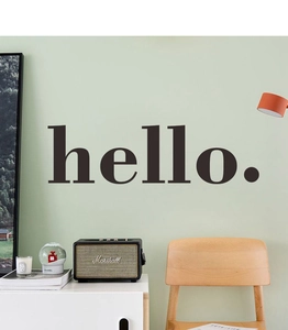 Minimalist matte black Hello wall decal applied on a light green living room wall background