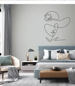 Detail of minimalist black metal line art featuring a female face with flower hat on wall