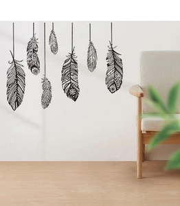 Détail de stickers muraux plumes noires et blanches de style bohème sur un mur de salon