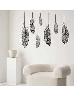 Détail de sept stickers muraux plumes noires bohèmes sur un mur blanc de salon minimaliste